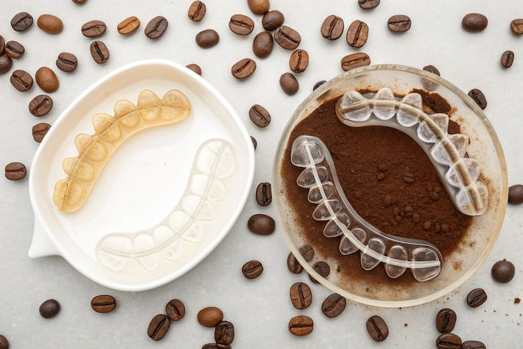 two bowls of coffee beans and Invisalign inside them, showing the effect of drinking coffee with Invisalign 