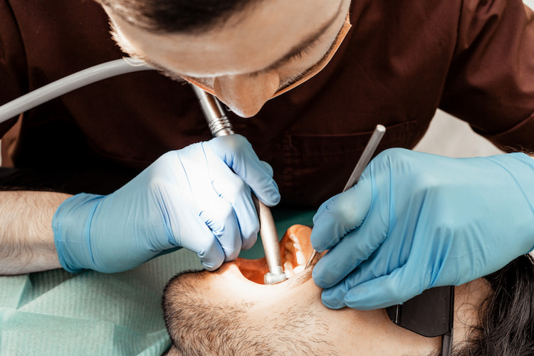 A male dentist treats performing endodontic treatment on a patient.